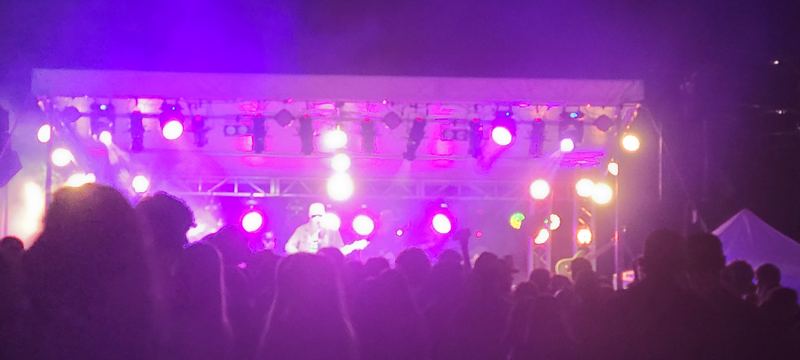 Outdoor festival stage with a purple-lit truss rig