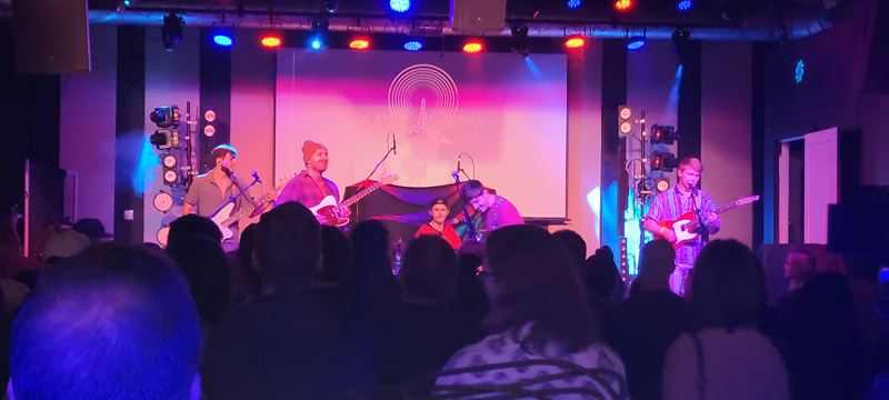 Band on a club stage lit in pink and blue